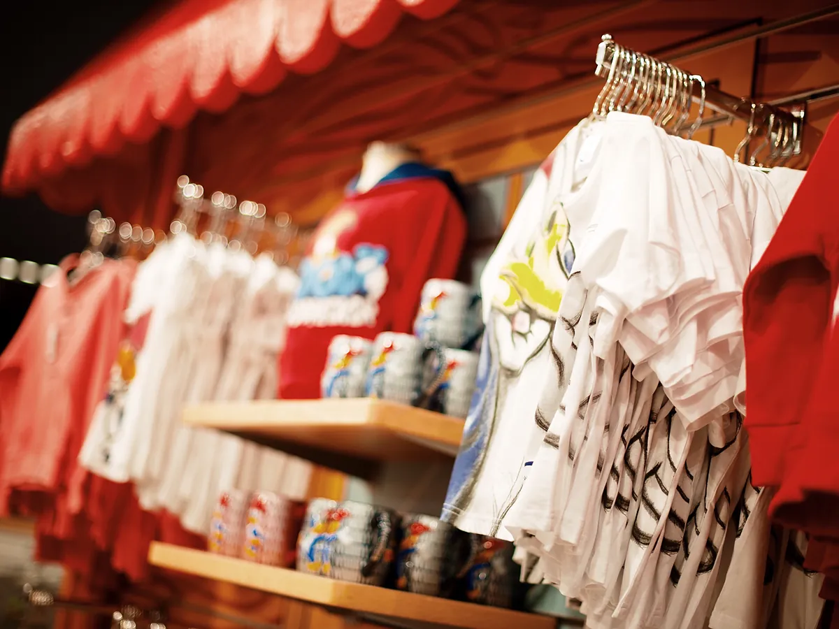 A stall of printed shirts and goods under an awning